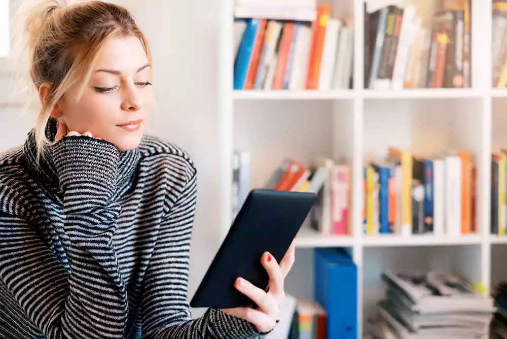 confira-os-beneficios-que-um-e-book-pode-trazer-para-suas-estrategias-de-venda Mulher com tablet na mão lendo um e-book