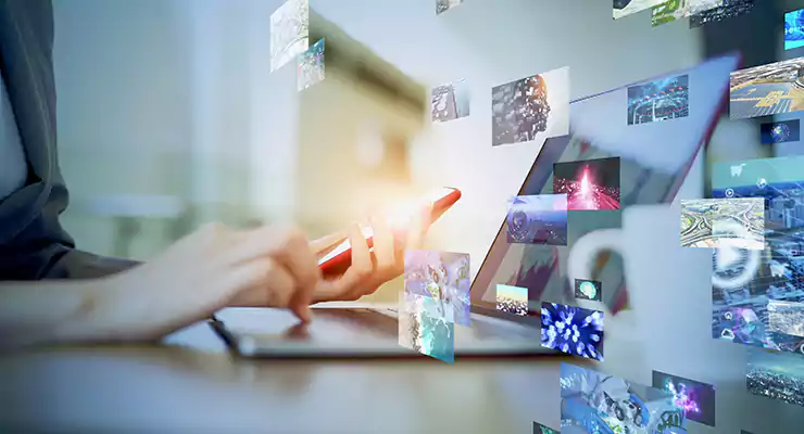 a-importancia-do-texto-alternativo-e-da-descricao-das-imagens Imagem para representar o conceito de conteúdo visual. Há um computador e celular aos fundos, com imagens diversas passando na frente.