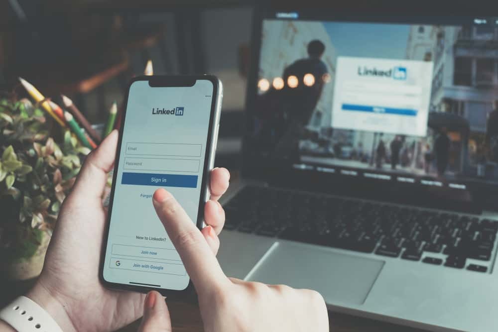textos-no-linkedin-dicas-para-se-destacar celular e tela de computador na tele de login do Linkedin