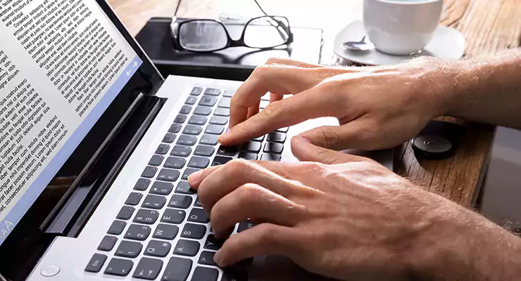 homem digitando texto no teclado de um notebook