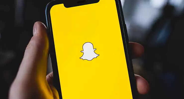 ainda-vale-a-pena-investir-em-marketing-no-snapchat logotipo do aplicativo snapchat na tela do smartphone na mão